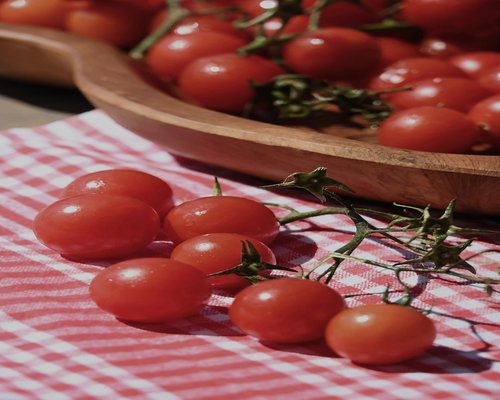 A variety of ripe seasonal tomatoes and avocados on a wooden surface